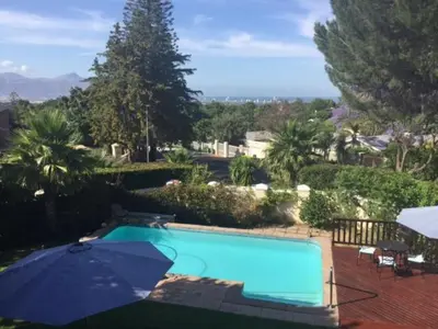 a swimming pool with an umbrella at Golf and Garden Guesthouse in Somerset West