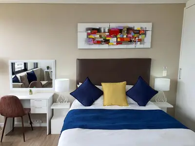 a bedroom with a bed with blue and yellow pillows at Manhattan Luxury Apartments in Cape Town