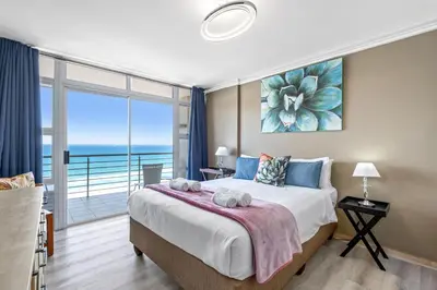 a bedroom with a large bed with a view of the ocean at The Waves 1002 in Bloubergstrand