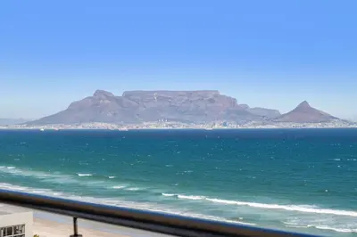 a view of the ocean with mountains in the background at The Waves 1002 in Bloubergstrand