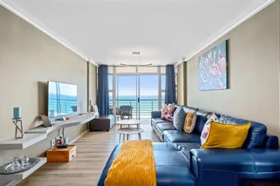 a living room with a blue couch and a table at The Waves 1002 in Bloubergstrand