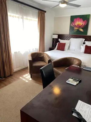 a hotel room with a bed and a table and chairs at Cotswold House in Cape Town