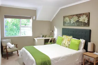 a bedroom with a bed with a green headboard and a window at Milas Place in Somerset West