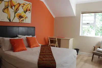 a bedroom with a bed with an orange wall at Milas Place in Somerset West