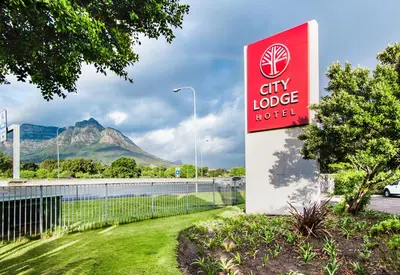 a sign for a city lodge hotel with a mountain in the background at City Lodge Hotel Pinelands in Cape Town