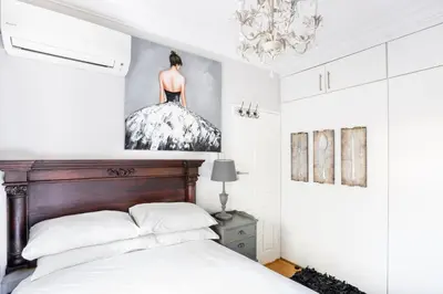 a bedroom with a bed with a dress on the wall at Avemore Wag n Bietjie No 1 in Stellenbosch