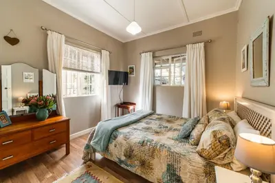 a bedroom with a bed and a dresser and a window at Belfield Wines and Farm Cottages in Grabouw