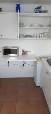 a kitchen with white cabinets and a microwave at Rose Cottage in Hermanus