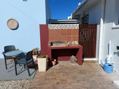 a patio with a table and chairs on a building at Rose Cottage in Hermanus