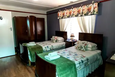 a room with two beds and a table and a window at Zoete Inval in Hermanus