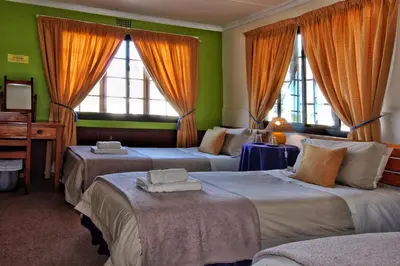 a hotel room with three beds and a piano at Zoete Inval in Hermanus