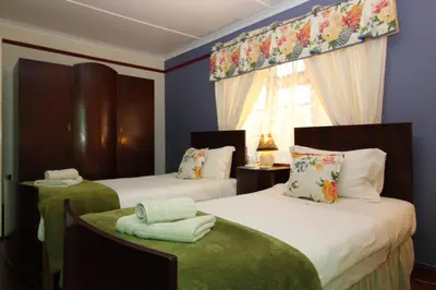 two beds in a room with blue walls at Zoete Inval in Hermanus