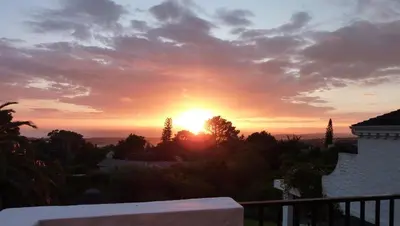 a sunset from the balcony of a house at Montrose Guesthouse in Somerset West