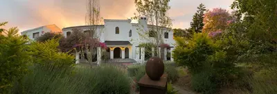 a large white house in the middle of a garden at Montrose Guesthouse in Somerset West