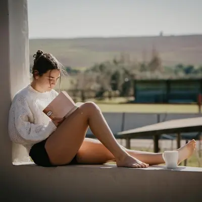 a woman sitting on a ledge reading a book at Doran Vineyards in Paarl