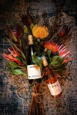 two bottles of wine sitting on a table with flowers at Doran Vineyards in Paarl