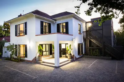 a white house with black windows and a staircase at Twice Central Guest House in Stellenbosch
