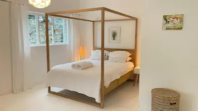 a bedroom with a canopy bed with white sheets and pillows at Pashasha Beach House and Hot Tub in Hermanus