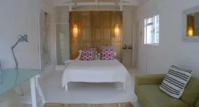 a white bedroom with a bed and a couch at Pashasha Beach House and Hot Tub in Hermanus