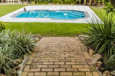 a brick path leading to a pool in a yard at KaapsePracht Bed & Breakfast in Somerset West