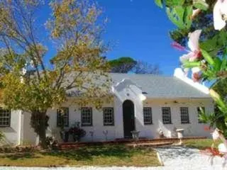 a white house with a tree in front of it at KaapsePracht Bed & Breakfast in Somerset West