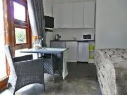 a kitchen with a table and a couch in a room at KaapsePracht Bed & Breakfast in Somerset West