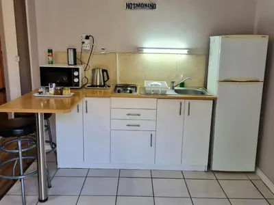 a kitchen with white cabinets and a white refrigerator at 10 Windell Self Catering Accommodation in Durbanville