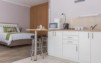 a kitchen with white cabinets and a bed in a room at 10 Windell Self Catering Accommodation in Durbanville