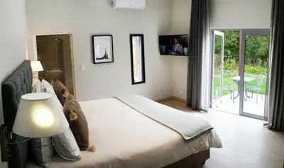 a bedroom with a bed with a lamp and a balcony at Vine Guesthouse in Stellenbosch