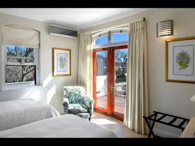 a bedroom with a bed and a chair and a window at 10 Villefranche in Franschhoek