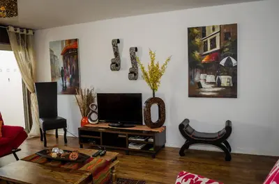 a living room with a television on a table at Greenways Emerald Bay in Strand