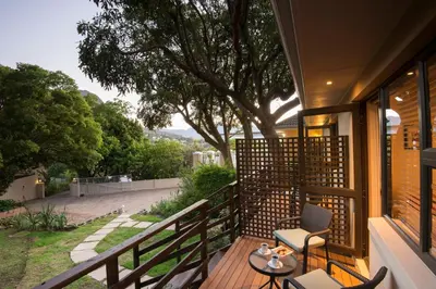 a balcony with chairs and a table and a tree at SomerZicht Guest House in Somerset West
