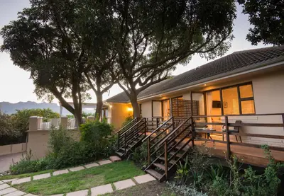 a house with a bench and a tree at SomerZicht Guest House in Somerset West