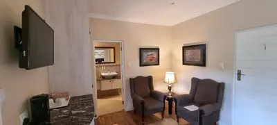 a living room with two chairs and a television at SomerZicht Guest House in Somerset West