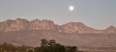 a view of a mountain range with the moon in the sky at SomerZicht Guest House in Somerset West