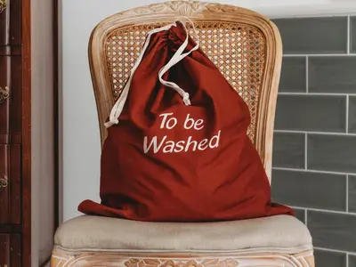 a red bag sitting on a chair with the words to be washed at Le Petit Paris in Franschhoek