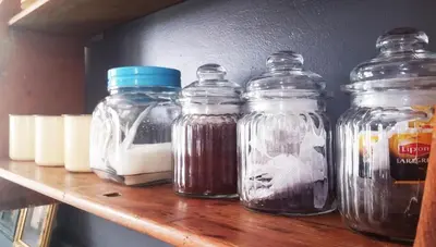 four glass jars sitting on a wooden shelf at Kimi's Cottage in Simondium