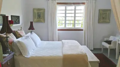 a bedroom with a white bed and a window at Kimi's Cottage in Simondium