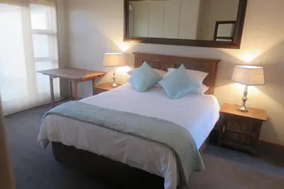 a bedroom with a large bed with two lamps and a mirror at Waves Echo in Bloubergstrand