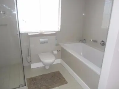 a bathroom with a tub and a toilet and a sink at Whale Rock 54 in Hermanus