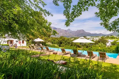 a pool with chairs and umbrellas in a yard at De Zalze Lodge in Stellenbosch