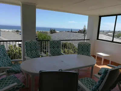 a balcony with a table and chairs and the ocean at Sit-en-Kyk in Hermanus