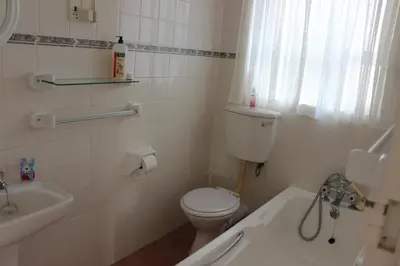 a white bathroom with a toilet and a sink at Sit-en-Kyk in Hermanus