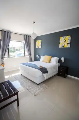 a bedroom with a white bed and a blue wall at New National Hotel and Conference in Parow