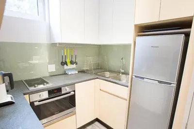 a small kitchen with a refrigerator and a sink at Laanhof Studios in Stellenbosch
