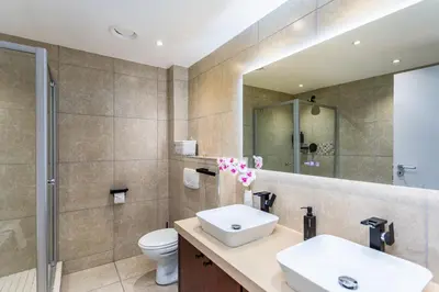 a bathroom with a sink and a toilet and a mirror at Knightsbridge Luxury Suite in Century City by CTHA in Cape Town