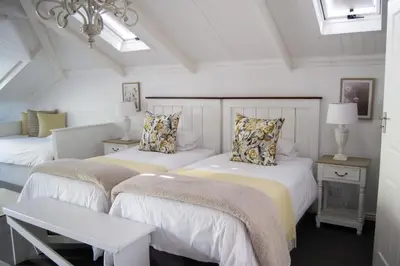 two beds in a room with white walls at Madeliefie Guest Accommodation in Paarl