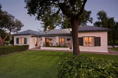 a white house with a tree in the yard at Allèe Bleue Wine Estate in Simondium