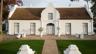 a white house with a brown roof at Allèe Bleue Wine Estate in Simondium
