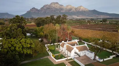 an aerial view of a house with mountains in the background at Allèe Bleue Wine Estate in Simondium